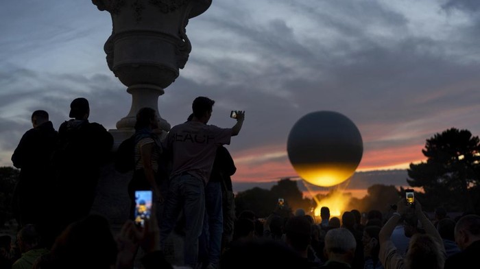 Menikmati Senja Paris yang Berhias Kaldron Olimpiade 2024 A crowd gathers at the gates to the Tuileries Garden to watch the cauldron rise at sunset during the 2024 Summer Olympics, Saturday, July 27, 2024, in Paris. (AP Photo/David Goldman)