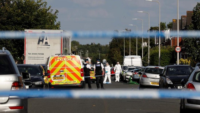 A police officer receives flowers and a stuffed animal from local residents to put them behind the police cordon near the scene of a stabbing incident in Southport, Britain, July 29, 2024. REUTERS/Temilade Adelaja