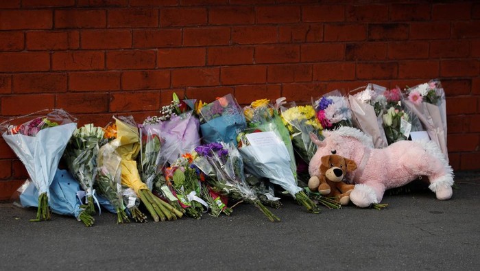 A police officer receives flowers and a stuffed animal from local residents to put them behind the police cordon near the scene of a stabbing incident in Southport, Britain, July 29, 2024. REUTERS/Temilade Adelaja
