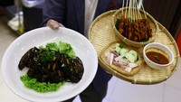 Pemilik restoran Francis Ng menunjukkan menu pasta tinta cumi dan sate yang ditaburi jangkrik dalam acara pameran hidangan berbahan dasar serangga di restoran House of Seafood di Singapura.