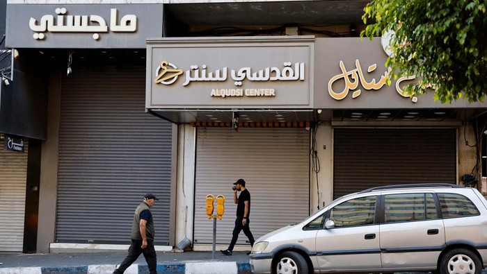 A Palestinian woman walks in front of closed shops during a general strike after the assassination of Hamas leader Ismail Haniyeh in Iran, in Hebron in the Israeli-occupied West Bank July 31, 2024.  REUTERS/Mussa Qawasma