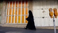 Seorang wanita berjalan di depan toko yang tutup di Tubas di Tepi Barat yang diduduki Israel.