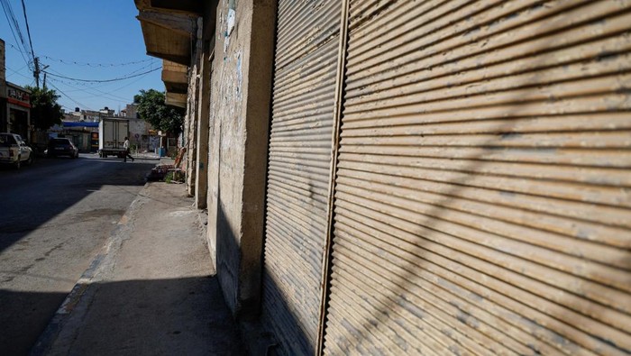 A Palestinian woman walks in front of closed shops during a general strike after the assassination of Hamas leader Ismail Haniyeh in Iran, in Hebron in the Israeli-occupied West Bank July 31, 2024.  REUTERS/Mussa Qawasma