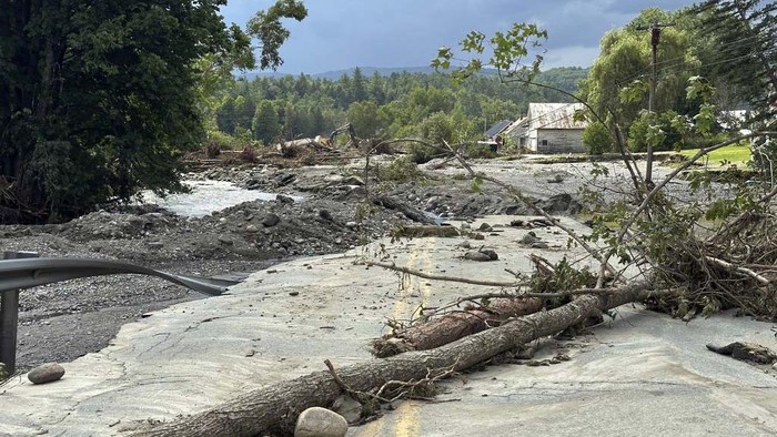 Trees sit across a roadway destroyed by flash floods in Lyndonville, Vt., Wednesday, July 31, 2024. Parts of the state hit by flooding Monday night and Tuesday are bracing again as a new round of severe thunderstorms moves through the region. (AP Photo/Nick Perry)