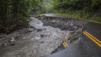 Sungai mengalir melewati jalan yang rusak akibat banjir bandang di Lyndonville, Vermont, AS, Rabu, 31 Juli 2024. 