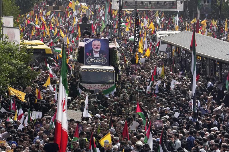 Iranians follow a truck, center, carrying the coffins of Hamas leader Ismail Haniyeh and his bodyguard who were killed in an assassination blamed on Israel on Wednesday, during their funeral ceremony at Enqelab-e-Eslami (Islamic Revolution) Sq. in Tehran, Iran, Thursday, Aug. 1, 2024. (AP Photo/Vahid Salemi)