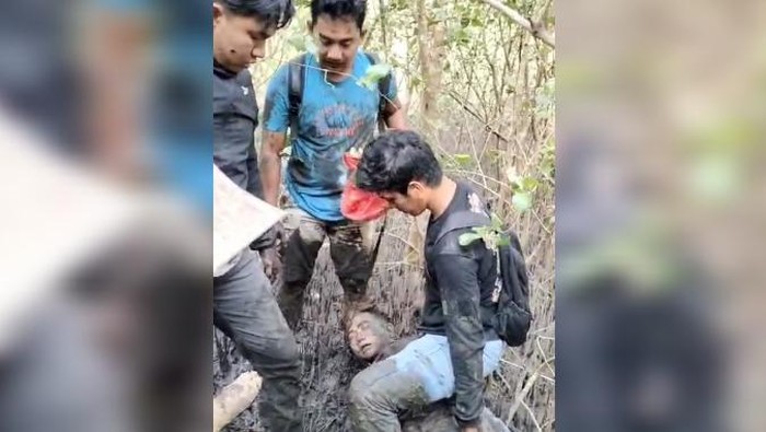 Tersangka saat diamankan di tengah hutan bakau penuh lumpur oleh polisi.