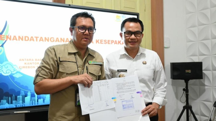 Pj Bupati Cirebon Wahyu Mijaya bersama Kepala BPJS Ketenagakerjaan Cabang Cirebon Novri Annur tunjukan penandatanganan MoU.