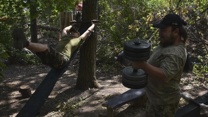 Soldiers of Ukraine's 65th Separate Mechanised Brigade drill with barbell and dumbbells on the frontline in Zaporizhzhia region, Ukraine, Wednesday, July 31, 2024. (AP Photo/Andriy Andriyenko)