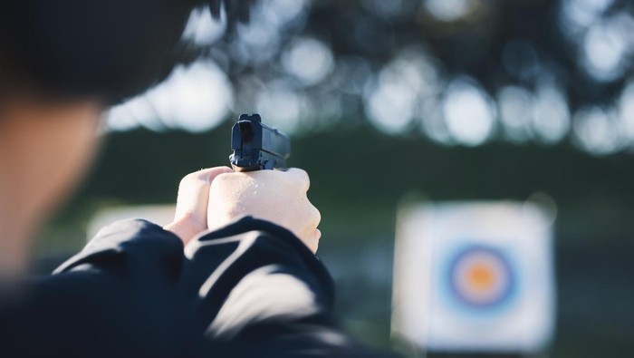 Firearm, target and person training outdoor at shooting range for game exercise or sports challenge closeup. Man hands with gun, circle and aim for practice, police academy or field practice mission