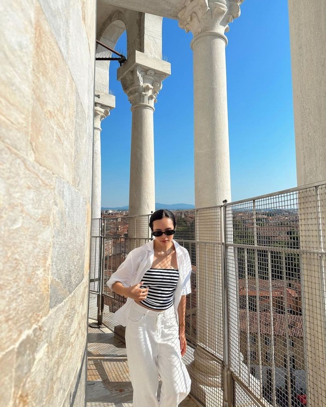 Seperti biasa, Beby tampil menawan dengan gayanya yang stylish. Ia memilih outfit monokrom saat berkunjung ke Menara Pisa. Celana panjang dan kemeja putih dipadukannya dengan crop top garis-garis serta kaca mata hitam. Foto: Instagram/@bebytsabina