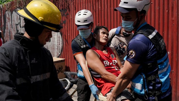 Rescuers carry a man during a fire at a building in Manila, Philippines, August 2, 2024. REUTERS/Lisa Marie David