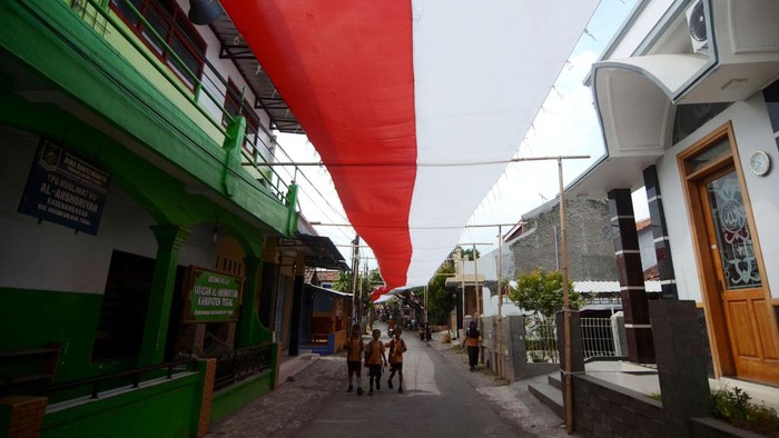 Sejumlah pelajar melintas dibawah bendera Merah Putih yang dibentangkan di atas jalan Desa Kademangaran, Kabupaten Tegal, Jawa Tengah, Jumat (2/8/2024). Bendera sepanjang 400 meter dan lebar tiga meter yang dijahit selama tiga bulan tersebut dipasang dalam rangka menyambut HUT ke-79 Kemerdekaan RI. ANTARA FOTO/Oky Lukmansyah/Spt.