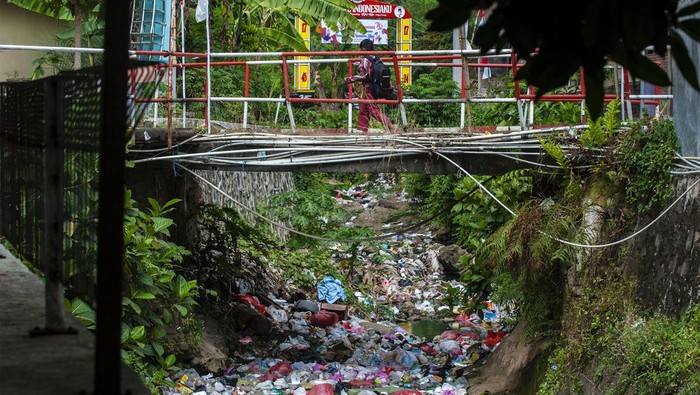 Seorang anak berjalan melintasi jembatan di atas kali Suralaya, Kota Cilegon, Banten, Jumat (2/8/2024). Tumpukan sampah limbah rumah tangga yang berasal dari kebiasaan warga membuang sampah sembarangan tersebut berpotensi menyumbat aliran air dan menyebabkan banjir. ANTARA FOTO/Muhammad Bagus Khoirunas/rwa.