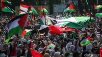 Massa melakukan estafet mengibarkan bendera Palestina dan bendera Merah Putih.