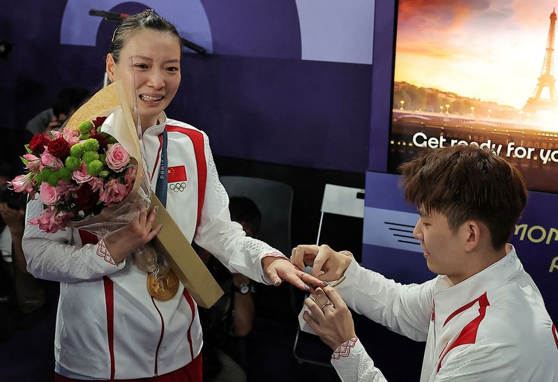 Paris 2024 Olympics - Badminton - Mixed Doubles Victory Ceremony - Porte de La Chapelle Arena, Paris, France - August 02, 2024. Liu Yuchen of China proposes to teammate Ya Qiong Huang of China after she won the gold.  REUTERS/Ann Wang  REFILE - CORRECTING ID FROM 