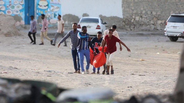 Relatives carry the body of a woman killed during an attack in Mogadishu on August 3, 2024. An Al-Shabaab suicide bomber and gunmen attacked a busy beachfront spot in the Somali capital Mogadishu killing at least seven people, police said Saturday. Police and witnesses told AFP the bomber detonated his device late Friday along Lido Beach -- popular with business people and officials and the scene of previous attacks -- before gunmen stormed the area. (Photo by Hassan Ali ELMI / AFP)