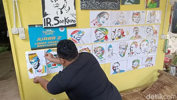 Yoga Bagus Wicaksana melukis menggunakan media limbah kardus obat apotek di rumahnya, Kelurahan Karangklesem, Kecamatan Purwokerto Selatan, Banyumas, Sabtu (3/8/2024).