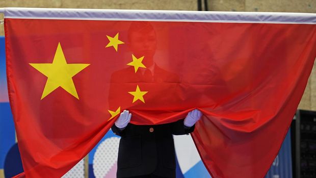 An Olympic official holds the Chinese flag as it is being raised during the medal ceremony of the 10m air pistol men's final at the 2024 Summer Olympics, Sunday, July 28, 2024, in Chateauroux, France. China's Xie Yu won the gold medal in the competition. (AP Photo/Manish Swarup)