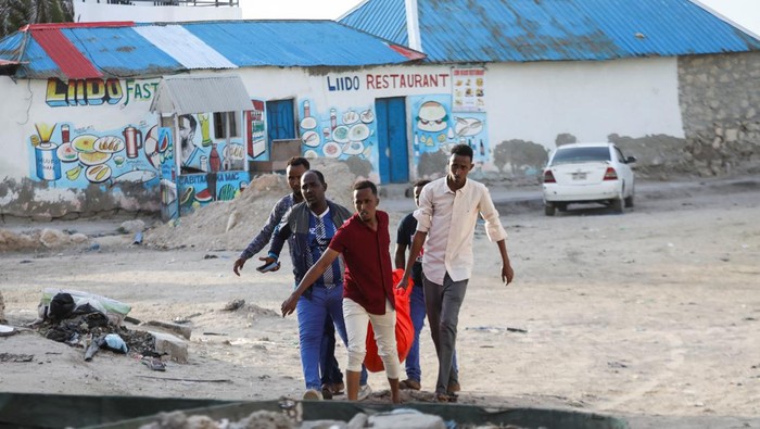 Horor Bom Bunuh Diri dan Penembakan di Somalia People carry the dead body of an unidentified woman killed in an explosion that occurred while revellers were swimming at the Lido beach in Mogadishu, Somalia August 3, 2024. REUTERS/Feisal Omar