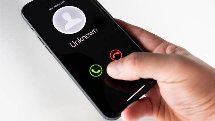 Adult right hand holding a mobile showing incoming unknown call