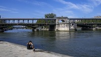 Seorang wanita menikmati matahari pagi di tepi Sungai Seine. AP/Dar Yasin