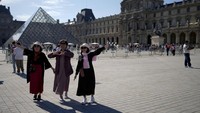 Turis berfoto di dekat Museum Louvre pada Olimpiade Musim Panas 2024. AP/Natacha Pisarenko