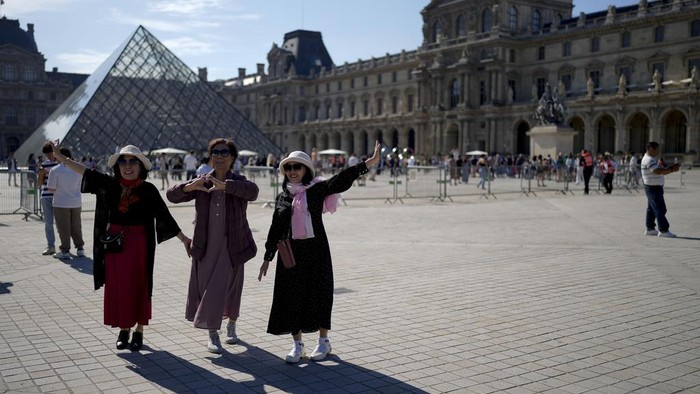 Menikmati Kota Paris di Tengah Gempita Pesta Olahraga Tourists take a picture near the Louvre Museum at the 2024 Summer Olympics, Sunday, July 28, 2024, in Paris, France. (AP Photo/Natacha Pisarenko)