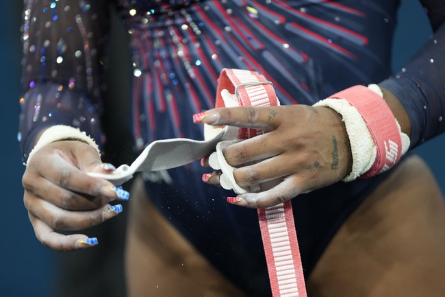 Jordan Chiles memilih warna biru untuk kuku jari tangan kanannya, sementara merah untuk kuku kirinya. Sentuhan warna emas di masing-masing jari seakan menjadi afirmasi yang berujung pada medali emas yang didapatnya dalam nomor grup. (Foto: AP Photo/Francisco Seco)