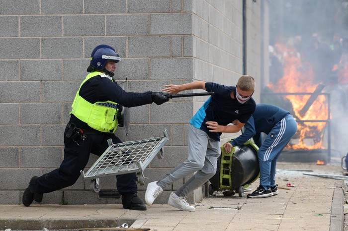 A demonstrator runs away from a police officer during an anti-immigration protest, in Rotherham, Britain, August 4, 2024. REUTERS/Hollie Adams
