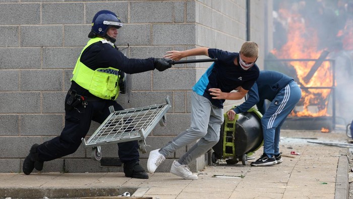 A demonstrator runs away from a police officer during an anti-immigration protest, in Rotherham, Britain, August 4, 2024. REUTERS/Hollie Adams