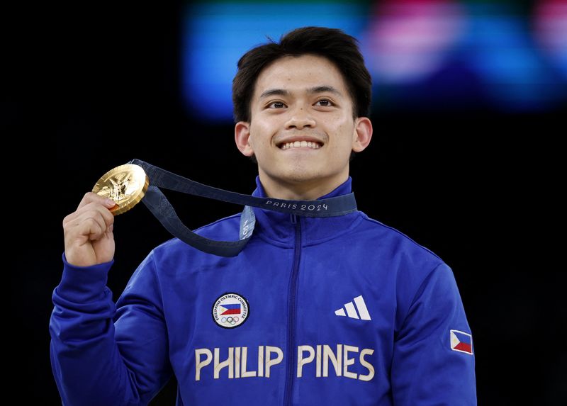 Paris 2024 Olympics - Artistic Gymnastics - Men's Vault Victory Ceremony - Bercy Arena, Paris, France - August 04, 2024. Gold medallist Carlos Edriel Yulo of Philippines celebrates with his medal on the podium. REUTERS/Amanda Perobelli