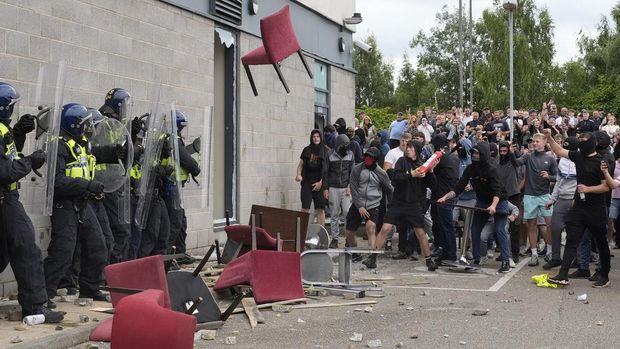 A chair is thrown at police officers as trouble flares during an anti-immigration protest outside the Holiday Inn Express in Rotherham, England, Sunday Aug. 4, 2024. (Danny Lawson/PA via AP)