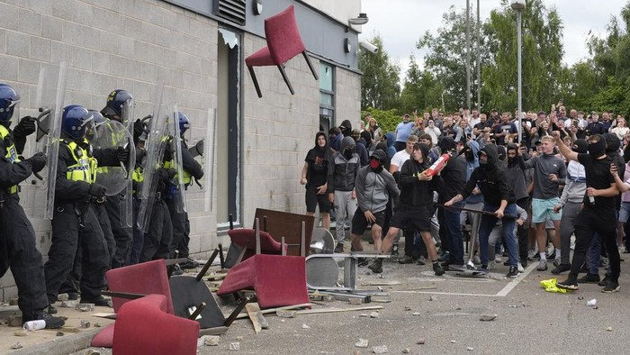 Hotel Hingga Toko di Inggris Jadi Rusak Akibat Kerusuhan A chair is thrown at police officers as trouble flares during an anti-immigration protest outside the Holiday Inn Express in Rotherham, England, Sunday Aug. 4, 2024. (Danny Lawson/PA via AP)
