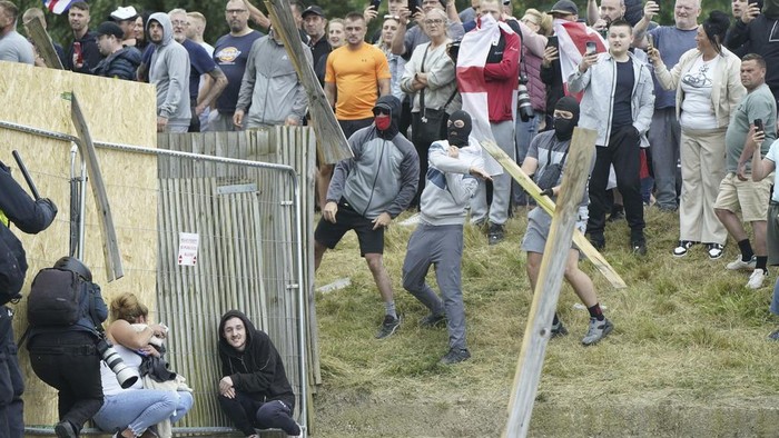 A chair is thrown at police officers as trouble flares during an anti-immigration protest outside the Holiday Inn Express in Rotherham, England, Sunday Aug. 4, 2024. (Danny Lawson/PA via AP)