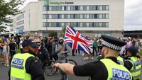 Petugas polisi berjaga di luar sebuah hotel selama protes anti-imigrasi di Rotherham, Inggris, Minggu (4/8). Ratusan pengunjuk rasa mengepung hotel yang digunakan untuk menampung migran di Inggris utara.
