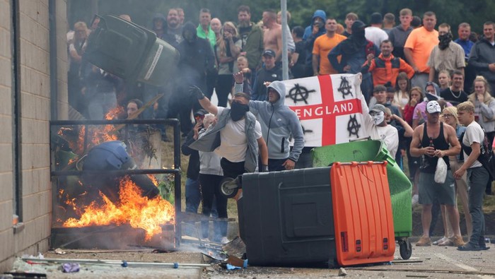 Demonstrators toss a trash bin during an anti-immigration protest, in Rotherham, Britain, August 4, 2024. REUTERS/Hollie Adams