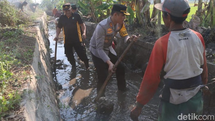 Kapolres Pasuruan Kota membantu warga membersihkan saluran irigasi