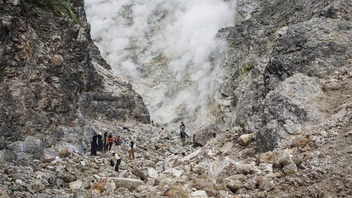 Pengunjung melihat asap dan belerang yang keluar dari dinding kawah Candradimuka di Gunung Lawu, Tawangmangu, Karanganyar, Jawa Tengah, Senin (5/8/2024). Kawah yang berada di jalur pendakian Cemara Kandang dengan ketinggian sekitar 2.550 mdpl tersebut menjadi lokasi favorit pendaki untuk singgah sekaligus melihat aktifitas vulkanik Gunung Lawu. ANTARA FOTO/Mohammad Ayudha/nz.