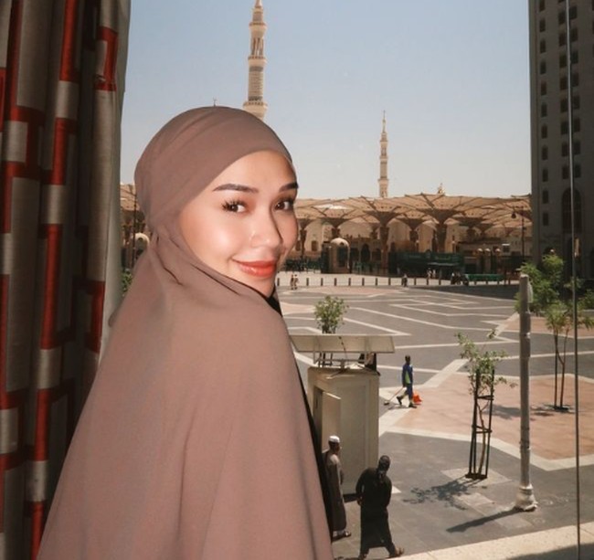 Dalam foto ini, Lula memilih French khimar berwarna cokelat bahan crinkle yang jatuh (flowy) selama di Tanah Suci. Pesinetron High School Love Story ini menggunakan riasan wajah natural look yang memberikan kesan segar dan bercahaya. Foto: Instagram/lulalahfah.