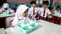 Para murid tampak lahap mengonsumsi makan gratis di jam makan siang.