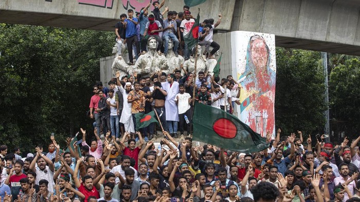 Protesters climb a public monument as they celebrate after getting the news of Prime Minister Sheikh Hasina's resignation, in Dhaka, Bangladesh, Monday, Aug. 5, 2024. (AP Photo/Rajib Dhar)