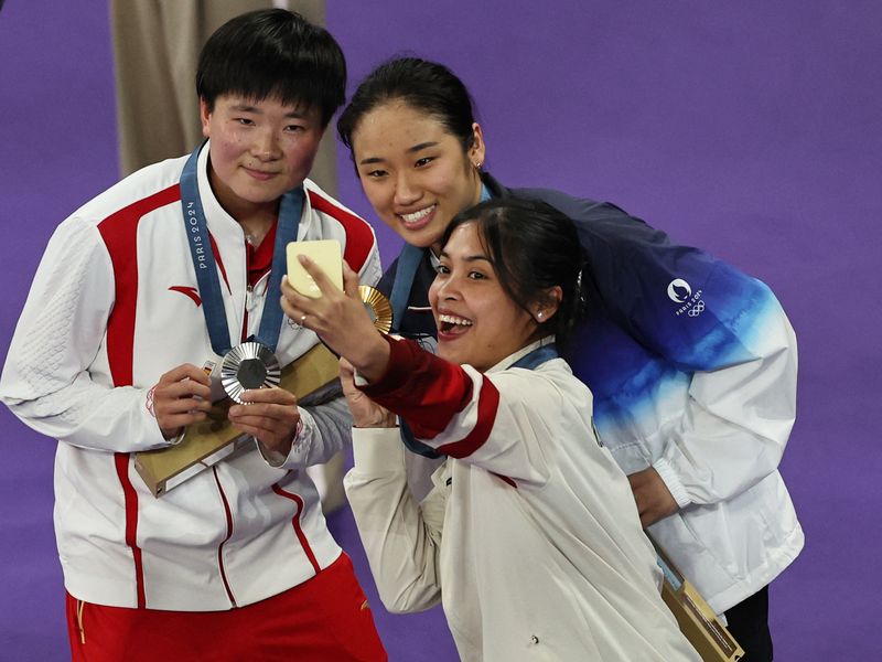 Paris 2024 Olympics - Badminton - Women's Singles Victory Ceremony - Porte de La Chapelle Arena, Paris, France - August 05, 2024. Gold medallist Se Young An of South Korea, silver medallist Bing Jiao He of China and bronze medallist Gregoria Mariska Tunjung of Indonesia take a selfie during the ceremony. REUTERS/Hamad I Mohammed