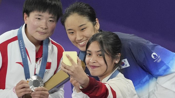 Senyum Gregoria Saat Raih Medali Perunggu Olimpiade Paris 2024 From left, medalists China's He Bingjiao, silver, South Korea's An Se-young, gold, and Indonesia's Gregoria Mariska Tunjung, bronze, celebrate on the podium of the badminton women singles at the 2024 Summer Olympics, Monday, Aug. 5, 2024, in Paris, France. (AP Photo/Dita Alangkara)