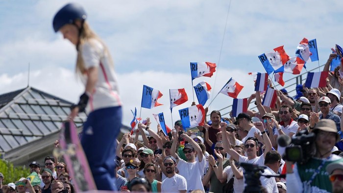 French fans cheer on Lucie Schoonheere, of France, in the foreground, during the women's skateboard street preliminaries at the 2024 Summer Olympics, Sunday, July 28, 2024, in Paris, France. (AP Photo/Frank Franklin II)