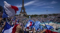 Pendukung Prancis mengibarkan bendera selama pertandingan voli pantai grup C putri antara Jerman dan Prancis di Stadion Menara Eiffel. AP/Louise Delmotte