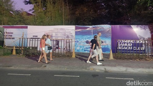 Beberapa turis saat berjalan di depan pembangunan Sanur Beach Club, Jalan Danau Tamblingan, Sanur, Denpasar, Bali, Jumat (19/7/2024). (Ni Made Lastri Karsiani Putri-detikBali)