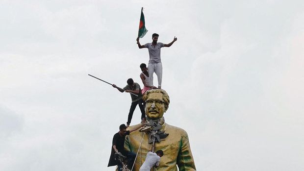 Orang-orang memanjat patung Sheikh Mujibur Rahman di kawasan Bijoy Sarani, saat merayakan pengunduran diri Perdana Menteri Sheikh Hasina di Dhaka, Bangladesh, 5 Agustus 2024. (REUTERS/Mohammad Ponir Hossain)