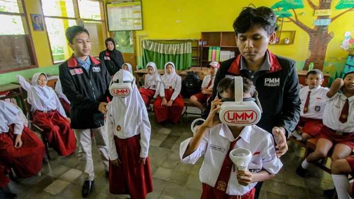 Dua mahasiswa Universitas Muhammadiyah Malang (UMM) mengarahkan siswa menggunakan teknologi virtual reality (VR) saat mengikuti kegiatan belajar mengajar di SDN 03 Tumpang, Malang, Jawa Timur, Selasa (6/8/2024). Pemanfaatan teknologi VR sebagai media pembelajaran tersebut bertujuan menciptakan lingkungan simulasi yang dapat dijelajahi para siswa sehingga kegiatan belajar di kelas lebih menarik dan interaktif. ANTARA FOTO/Muhammad Mada/Spt.