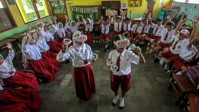 Pemanfaatan teknologi virtual reality di bidang pendidikan Dua mahasiswa Universitas Muhammadiyah Malang (UMM) mengarahkan siswa menggunakan teknologi virtual reality (VR) saat mengikuti kegiatan belajar mengajar di SDN 03 Tumpang, Malang, Jawa Timur, Selasa (6/8/2024). Pemanfaatan teknologi VR sebagai media pembelajaran tersebut bertujuan menciptakan lingkungan simulasi yang dapat dijelajahi para siswa sehingga kegiatan belajar di kelas lebih menarik dan interaktif. ANTARA FOTO/Muhammad Mada/Spt.